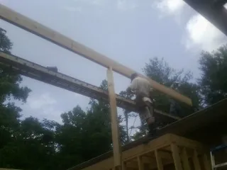 Carpenter setting a ridge beam over a new addition frame — Ice Dam Removal by Roofing Brothers in Nesbit