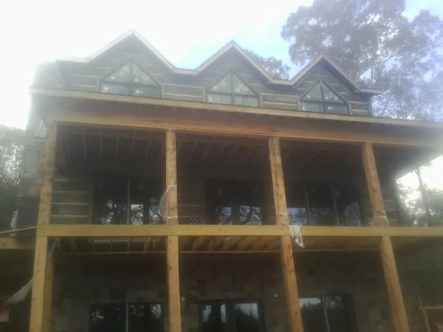 Dormers and porch framing on a large log home under construction — Roof Coating work by our crew in Nesbit