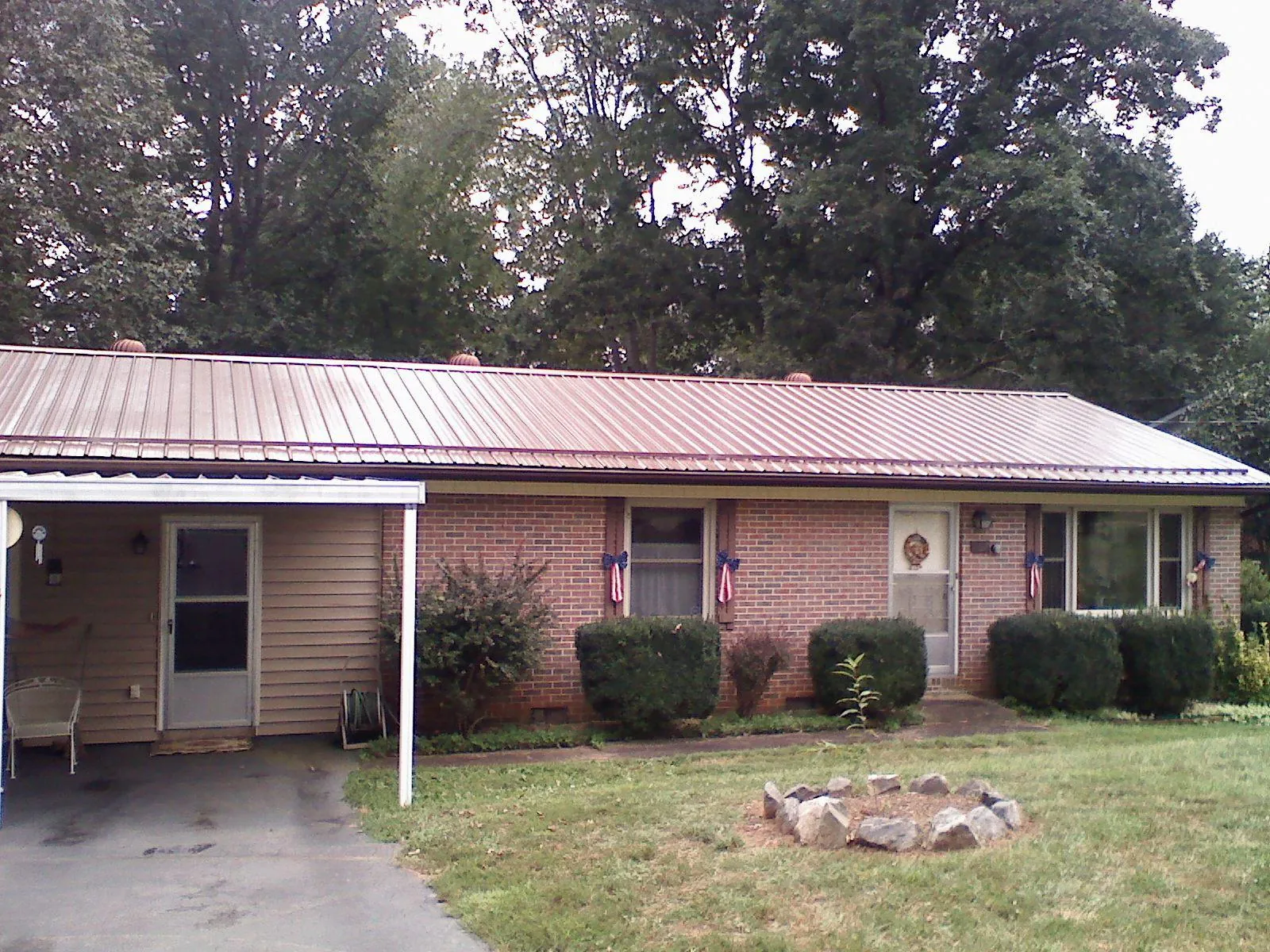 Bronze metal roof and carport on a brick ranch home — Roof Repair work by our crew in Nesbit